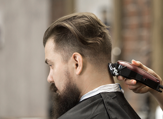 Cropped unrecognizable male barber with razor and sharpening